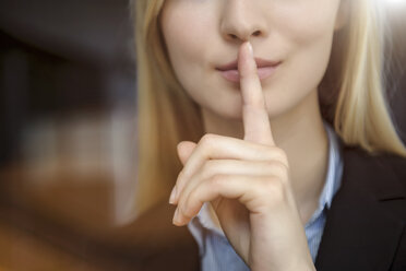 Nahaufnahme eines Bildes einer jungen Geschäftsfrau mit Finger auf den Lippen - ISF15446