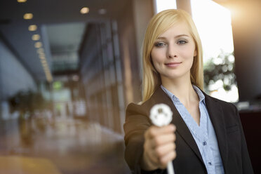 Porträt einer jungen Geschäftsfrau, die ein Netzstromkabel im Büro hochhält - ISF15447