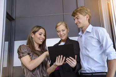 Geschäftsfrauen und Geschäftsleute nutzen ein digitales Tablet zur Diskussion - ISF15455