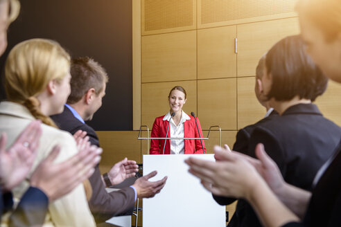 Das Publikum applaudiert einer jungen Geschäftsfrau im Konferenzraum - ISF15483