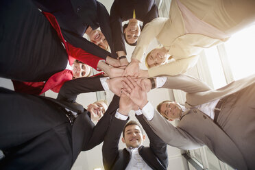 Low angle view of group of businesswomen and men in a circle with hands together - ISF15486