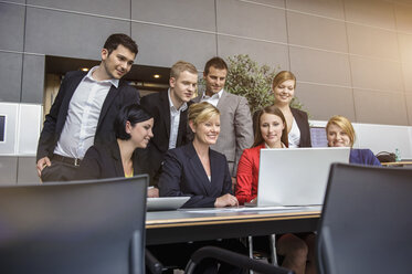 Geschäftsfrau und Büroteam mit Blick auf den Laptop - ISF15494