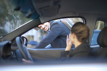 Young businesswoman driving and waving at male cyclist - ISF15534