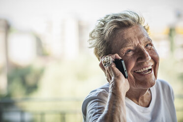 Eine sehr ältere Frau plaudert und lacht mit ihrem Smartphone auf dem Balkon ihrer Wohnung - ISF15603