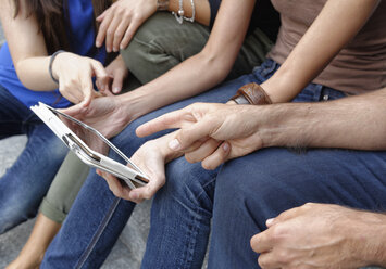 Gruppe von Freunden mit Blick auf ein digitales Tablet, Fokus auf Tablet und Hände - CUF38661