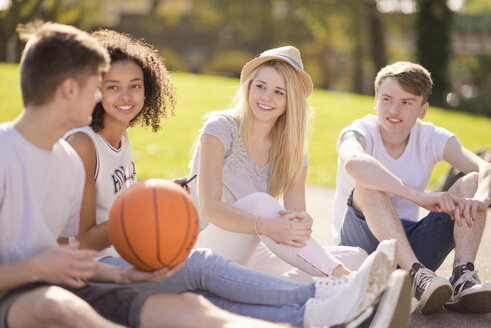 Vier junge erwachsene Basketballspieler sitzen und unterhalten sich - CUF38670