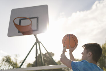 Junger Mann versucht, einen Basketball in einen Basketballkorb zu werfen - CUF38683