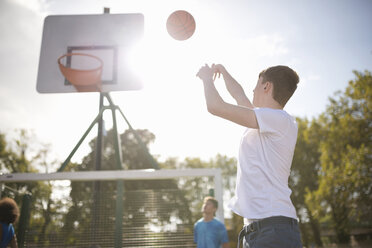 Junger männlicher Basketballspieler wirft Basketball in den Korb - CUF38684