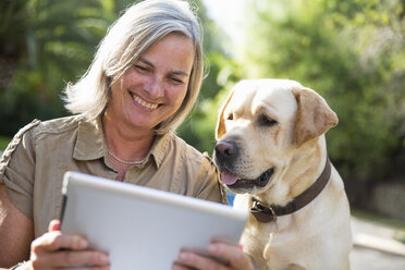 Woman and dog looking at digital tablet - CUF38714