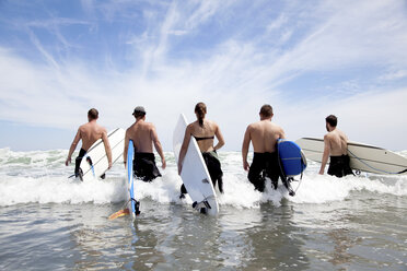 Rückansicht einer Gruppe von männlichen und weiblichen Surferfreunden, die mit Surfbrettern ins Meer waten - ISF15644