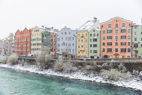 Österreich, Innsbruck, bunte Häuserzeile im Winter mit Inn im Vordergrund, lizenzfreies Stockfoto