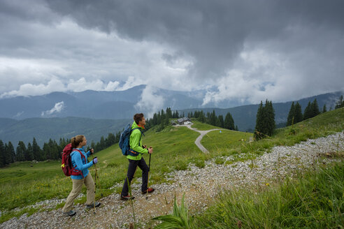 Deutschland, Lenggries, junges Paar mit Wanderstöcken beim Aufstieg - LBF02001