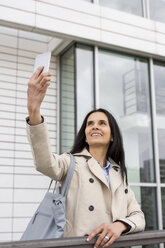 Portrait of smiling woman taking selfie with cell phone - JUNF01076