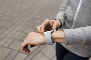 Woman's hand adjusting settings of smartwatch, close-up - JUNF01083