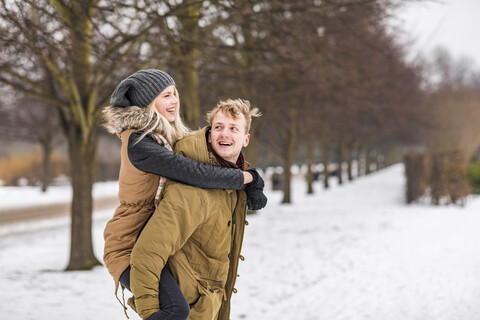 Happy young man giving his girlfriend a piggyback ride stock photo