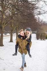 Young man giving his girlfriend a piggyback ride in winter - WPEF00571