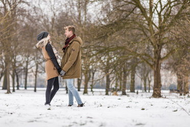 Junges verliebtes Paar steht Hand in Hand in einem Park im Winter - WPEF00576