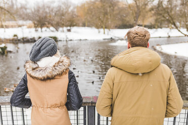 Rückenansicht eines jungen Paares, das im Winter im Park nebeneinander steht - WPEF00580