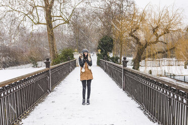 Teenager-Mädchen steht an einem verschneiten Tag auf einem Steg in einem Park - WPEF00581