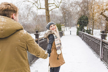 Porträt eines glücklichen Mädchens im Teenageralter, das Hand in Hand mit ihrem Freund an einem verschneiten Tag auf einem Steg steht - WPEF00584