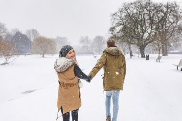 Glückliches Teenager-Mädchen, das mit ihrem Freund im Park im Schnee spazieren geht - WPEF00588