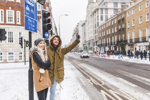 UK, London, junges Paar steht am Straßenrand und ruft im Winter ein Taxi - WPEF00589