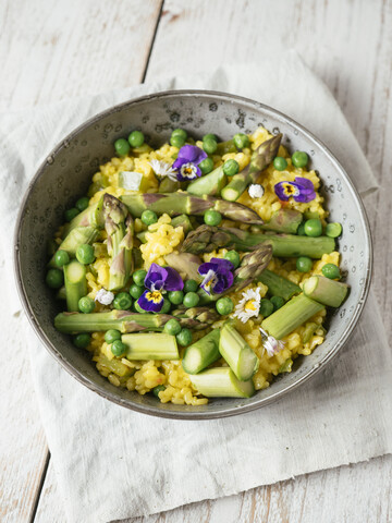 Risotto with green asparagus and peas, garnished with edible flowers stock photo