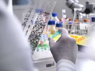 Scientist holding a DNA gel revealing the genetic make up of the specimen in the vial - ABRF00185