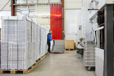 Factory workers moving containers of cardboard - CUF38745