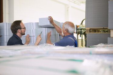 Factory workers moving and stacking cardboard - CUF38778