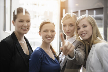 Businesswomen looking and pointing on glass - CUF38805