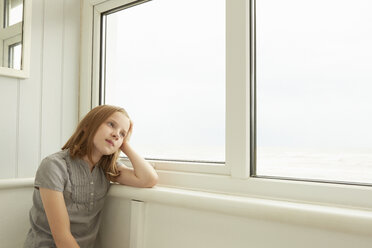 Porträt eines Mädchens, das aus dem Fenster seiner Ferienwohnung blickt - CUF38829