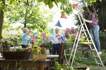 Grandparents and granddaughter hanging up bunting - CUF38839