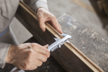 Carpenter measuring wood plank with vernier caliper in factory, Jiangsu, China - CUF38854