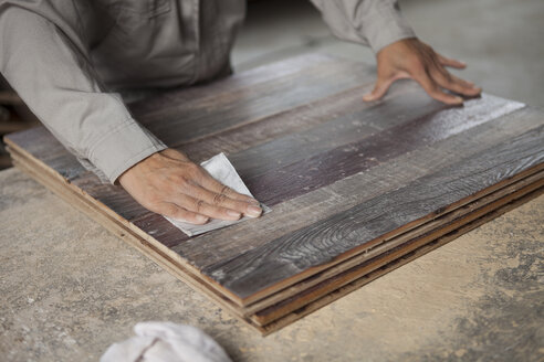 Zimmermann glättet die Oberfläche eines Holzbretts mit Schleifpapier in einer Fabrik, Jiangsu, China - CUF38856