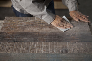 Carpenter smoothing surface of wood plank with sandpaper in factory, Jiangsu, China - CUF38858