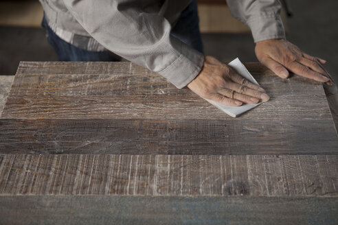Zimmermann glättet die Oberfläche eines Holzbretts mit Schleifpapier in einer Fabrik, Jiangsu, China - CUF38858