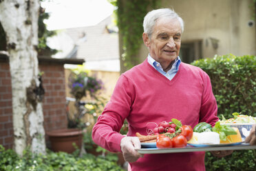 Älterer Mann trägt Tablett mit frischen Lebensmitteln - CUF38866
