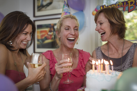 Drei reife Frauen auf einer Geburtstagsfeier, lachend, lizenzfreies Stockfoto