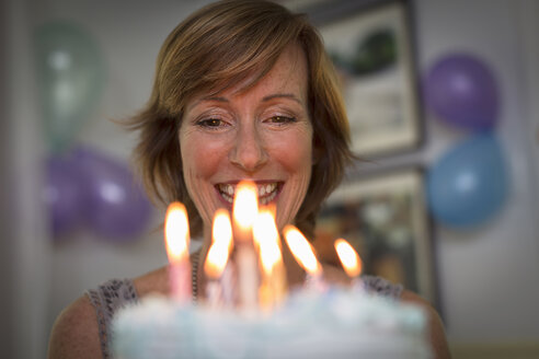Ältere Frau hält Geburtstagskuchen mit Kerzen - ISF15710