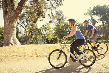 Mature couple cycling in park - ISF15755