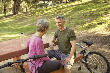 Älteres Radfahrerpaar macht eine Pause am Picknicktisch im Park - ISF15762