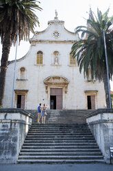 Rear view of young couple looking up at church, Milna, Brac, Croatia - ISF15785