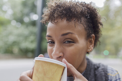 Nahaufnahme einer reifen Frau, die einen Kaffee zum Mitnehmen im Park trinkt, lizenzfreies Stockfoto