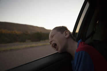 Junge lehnt sich mit geschlossenen Augen und offenem Mund aus dem Autofenster - ISF15833