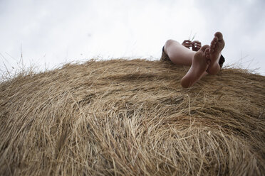 Feet of teenage boy lying on haystack, South Dakota, USA - ISF15855