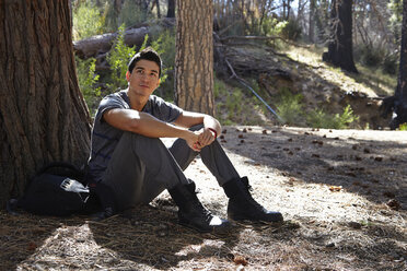 Portrait of young man sitting in forest, Los Angeles, California, USA - ISF15874