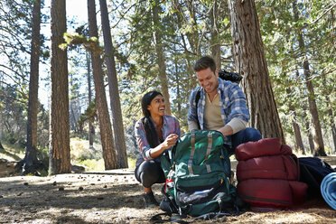 Young couple unpacking camping rucksack in forest, Los Angeles, California, USA - ISF15879