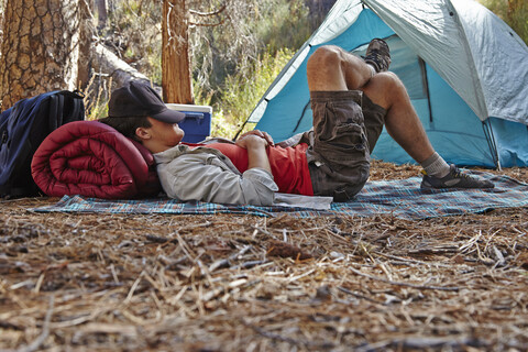 Junger männlicher Camper beim Ausruhen im Wald, Los Angeles, Kalifornien, USA, lizenzfreies Stockfoto