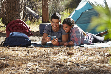 Junges Camping-Paar schaut im Wald auf sein Smartphone, Los Angeles, Kalifornien, USA - ISF15893